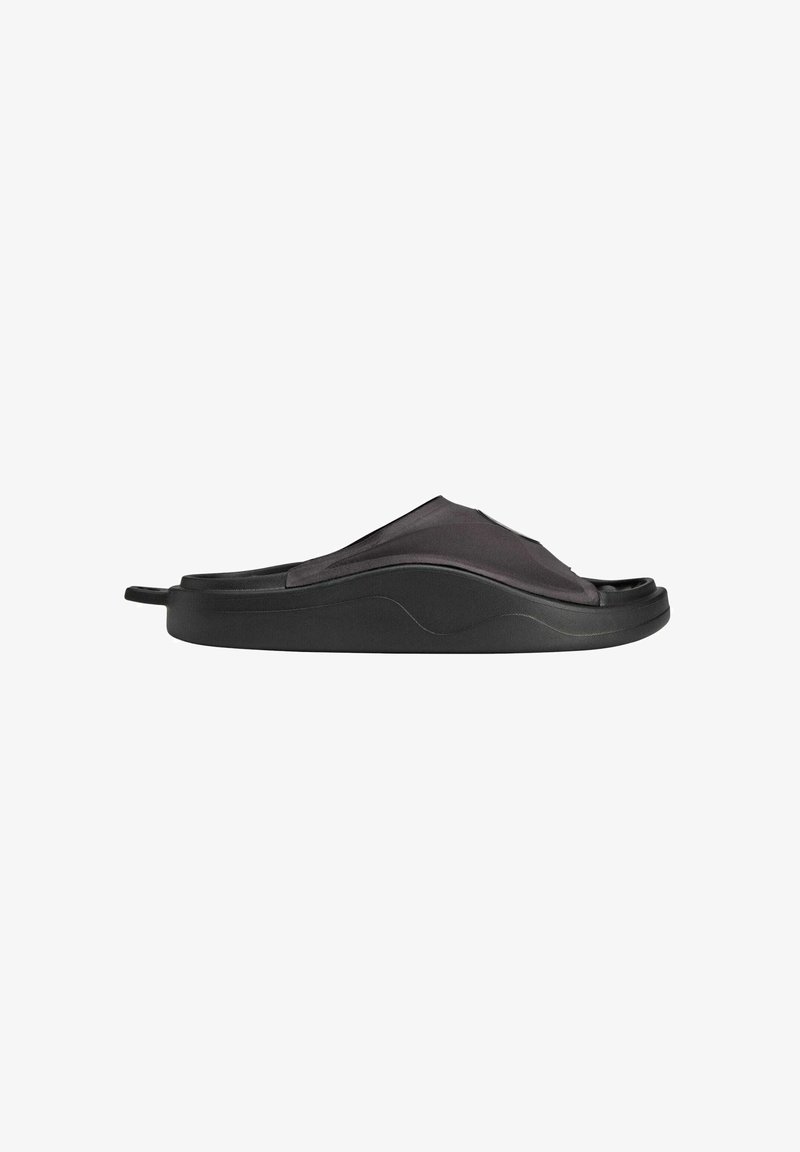 Black slip-on sandal with a smooth, curved design; made of flexible material; features a textured upper and a supportive sole.