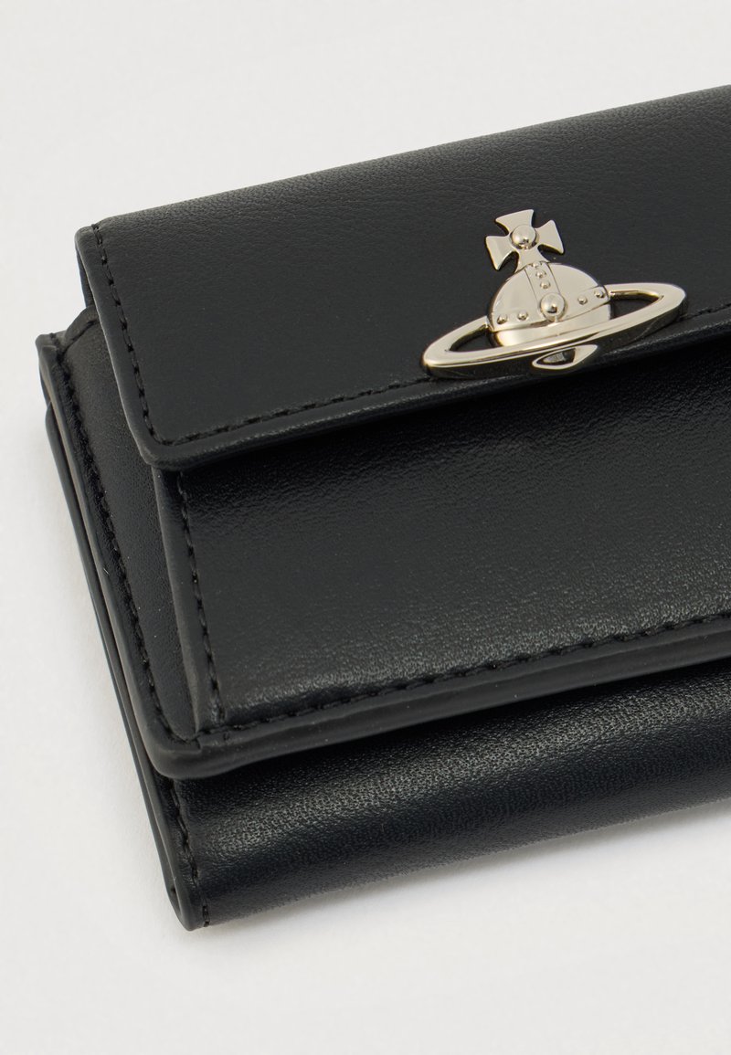 Portefeuille en cuir noir à texture lisse, doté d'une attache argentée en forme de Saturne et de détails de couture le long des bords.