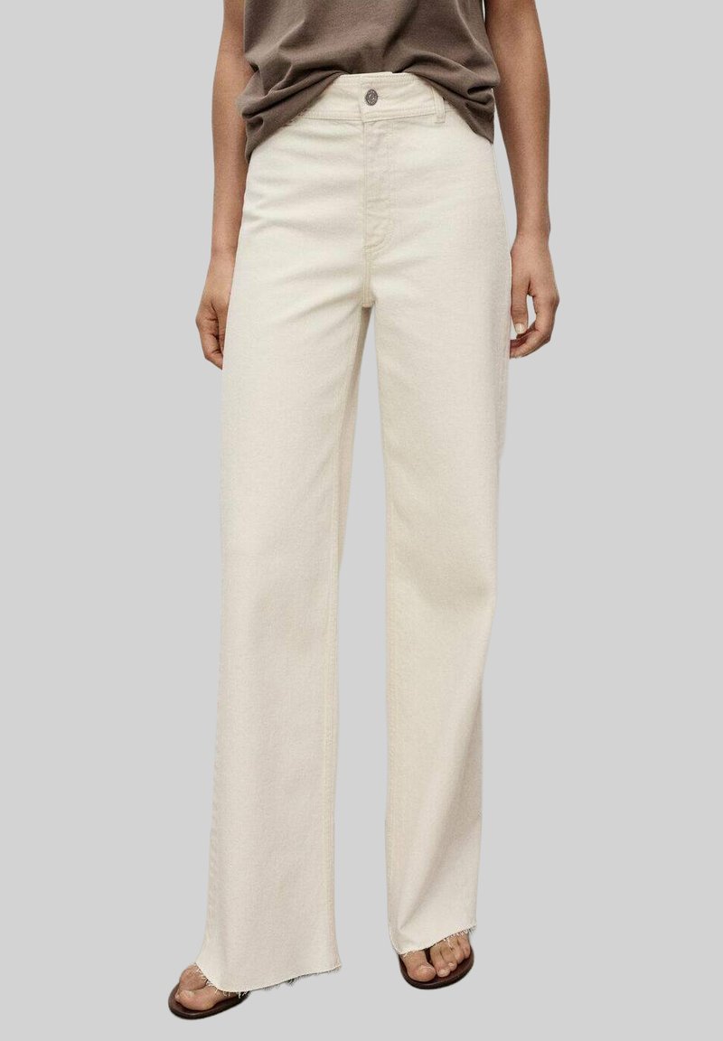 Cream wide-leg jeans made of denim, featuring a button closure, high waist, and raw hem. Paired with a relaxed-fit brown top.