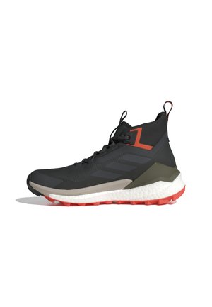 Zapatillas altas negras con un upper texturizado, acentos naranjas en contraste, una suela resistente con detalles rojos y una media suela blanca acolchada.