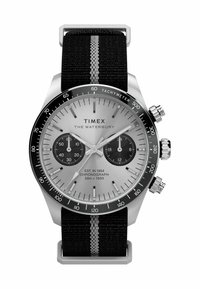 Reloj cronógrafo Timex con esfera plateada, bisel negro con taquímetro y correa de tela negra con una franja blanca. Dos subesferas y marcadores plateados.