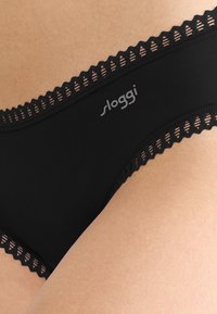 Svart Sloggi-underkläder med ett spetsdekorerat midjeband med utskurna mönster. Slät tygtextur med en högskuren design för komfort.