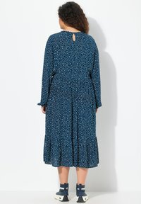 Sinihan sininen mekko valkoisilla pilkkuilla, pitkät hihat, pyöreä kaula-aukko avauksella, joustava vyötärö ja liehuva helma. Yhdistettynä sinisiin nilkkasaappaisiin.