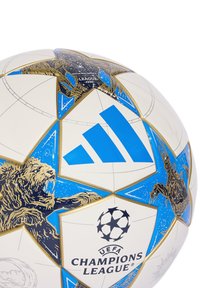 Valkoinen ja sininen UEFA Champions League -jalkapallo, jossa on kultaiset leijona- ja skorpioni-kuvasto sekä Adidas-logo.