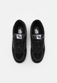 Sorte semskete joggesko med hvite sømmer, rund tå, snøring, og Vans-logo på tungen; strukturert stoff og polstret krage.