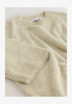 Beige huňatý pletený svetr s metalickými vlákny a oválným výstřihem, rozložený na plochu, na kterém je vidět etiketu značky NEXT uvnitř límce.