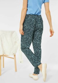 Pantaloni blu a fantasia realizzati in tessuto leggero, con una vestibilità comoda e un elastico in vita. Indossati con sneaker bianche e una camicia leggera.