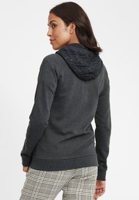 Mörkgrå hoodie med en strukturerad kabelstickad huva, som har en tajt passform och ribbade muddar och nederkant. Matchas med byxor med rutigt mönster.