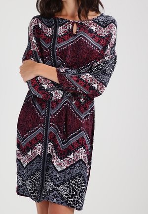 Robe à motifs rouge et marine avec des manches longues, présentant un décolleté en forme de clé, et un design géométrique avec des accents floraux et un tissu texturé.
