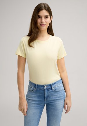 T-shirt di cotone giallo chiaro, con scollo rotondo e maniche corte. Abbinato a jeans blu chiaro in denim con vestibilità classica e design a cinque tasche.