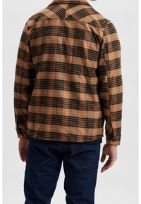 Camicia a quadri marrone e nera con dettagli gialli. Presenta un colletto classico e maniche lunghe, realizzata in un tessuto testurizzato.