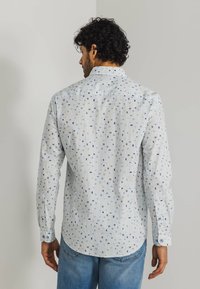 Langarmshirt van lichte stof, met een witte basis en vierkante patronen in blauw en beige, een klassieke kraag en knoopmanchet.