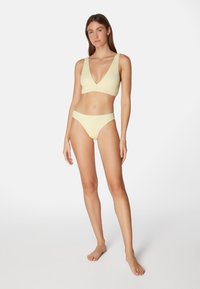 Gul texturerad bikini-set med en djup V-ringad bralette och matchande lågt skurna trosor, med sömlös finish och minimal hårdvara.