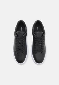Schwarze Leder-Sneaker mit glatter Textur, weißen Gummisohlen und schwarzen Schnürsenkeln. Markenlogo auf der Innenseite sichtbar.