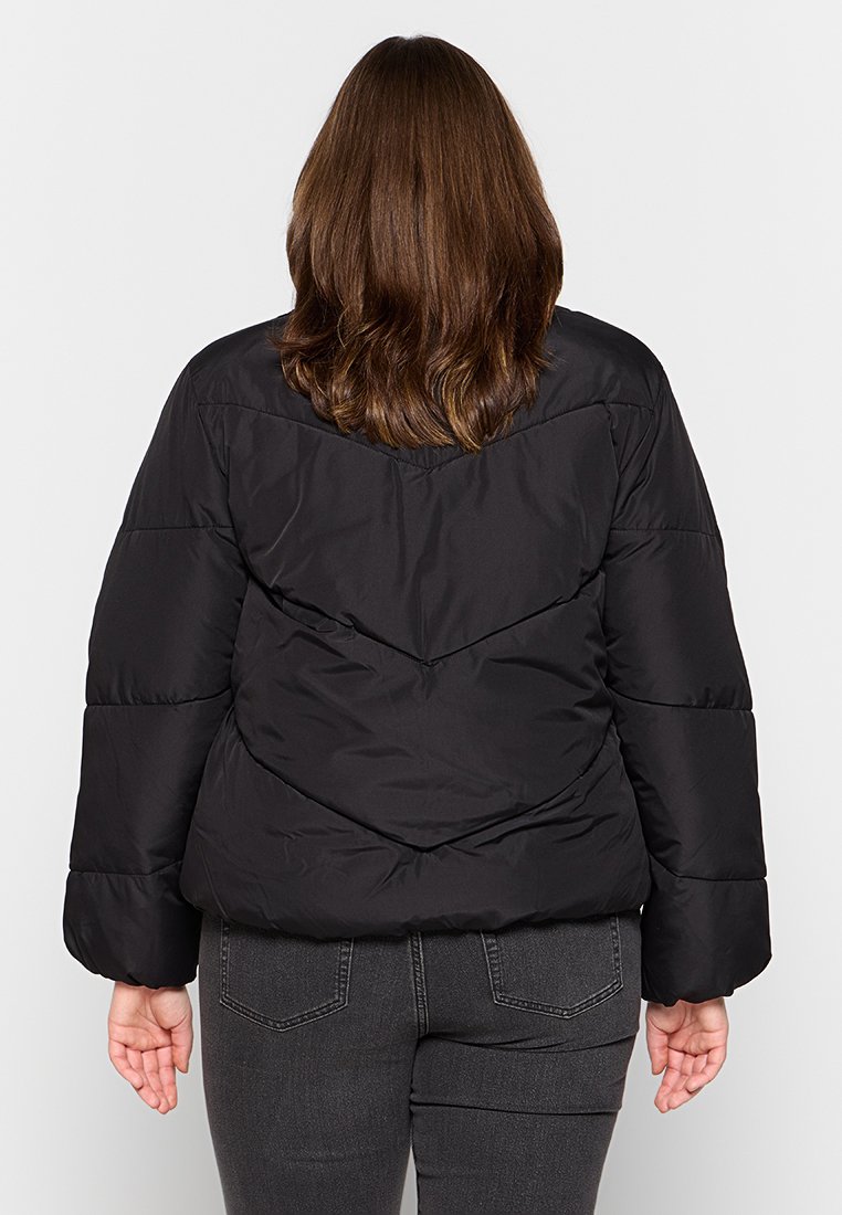 Giacca a vento nera con design a zigzag, imbottitura spessa e maniche ampie. Il materiale appare liscio con una finitura lucida.