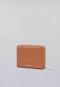 Billetera compacta de cuero marrón claro con cierre de cremallera y logo plateado "Trussardi" en la parte frontal, sobre un fondo gris liso.