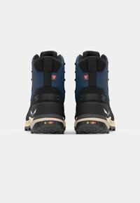 Vidēja augstuma pārgājienu zābaki ar zilu augšdaļu, melnām detaļām un teksturētām gumijas zolēm. Ir aizmugurējais cilpiņa un krāsaini metāla akcenti.