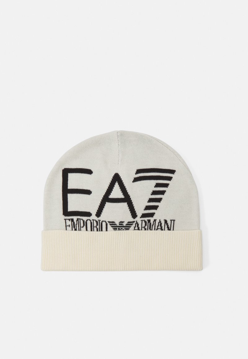 Cappello beanie in grigio chiaro, con logo nero recante il testo "EA7 Emporio Armani". Progettato con un orlo ribbed di colore crema nella parte inferiore.