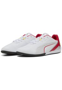 Scarpe da ginnastica bianche con accenti rossi, design con lacci, lati perforati e suola in gomma nera. Presentano dettagli gialli vicino ai lacci.