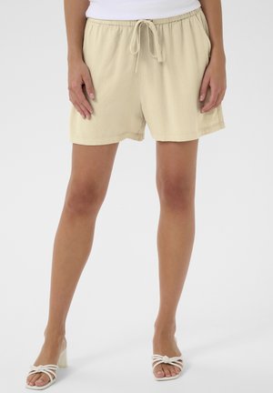 Beežist linastest lühikesed püksid, lõdva istumise ja nööridega vöökoht. Omab külgtaskuid ja sirget allääret. Sile tekstuur.