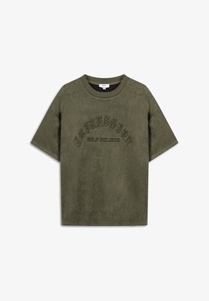 Olivegrünes T-Shirt mit kurzen Ärmeln, aus weichem Stoff gefertigt. Mit gesticktem Text „IMPRESSION SELF BELIEVE“ in bogenförmiger Anordnung.