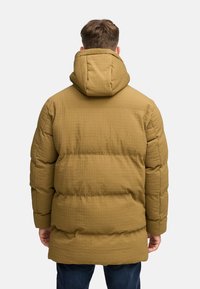 Khaki-pudret parka-jakke med en tekstureret overflade, hætte og elastiske manchetter, der har et quiltet mønster for varme og komfort.