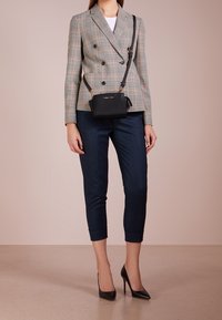 Béžový, černý a červený kostkovaný dvouřadý blazer, spárovaný s námořnickými zkrácenými kalhotami a černými stiletto podpatky. Černá crossbody taška.