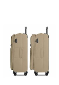 Deux valises souples beige avec des poignées télescopiques prolongées et des poignées latérales, vues de côté sur quatre roues noires.