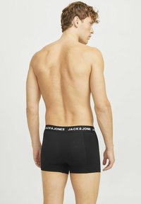 Boxers en coton noirs avec une large ceinture élastique arborant la marque "JACK & JONES", vus de dos. Texture lisse.