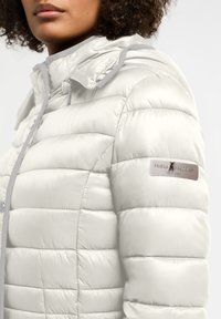 Lichte, pufferjack in off-white nylon met grijze accenten; heeft een ritsluiting, afneembare capuchon en gestikte quilting.