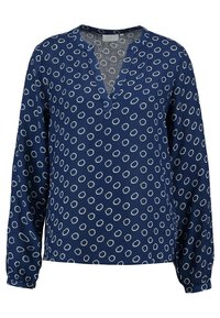 Blouse bleu marine avec un col en V et des manches longues, présentant un motif circulaire blanc sur toute la surface. Tissu doux avec une coupe décontractée.