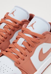 Baskets Nike Air Jordan blanches et rose poudré avec des lacets tressés et le logo Jumpman sur la languette.