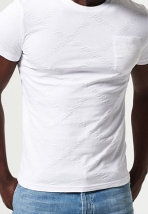 Man draagt een eenvoudig wit T-shirt met korte mouwen en een borstzakje, gecombineerd met lichtblauwe spijkerbroek, gezien van de taille tot boven.