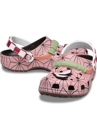 Rosa Plastikclogs mit einem Netzmuster. Merkmale sind ein grüner Riemen und schwarze Akzente. Perforiertes Design für Atmungsaktivität und Komfort.