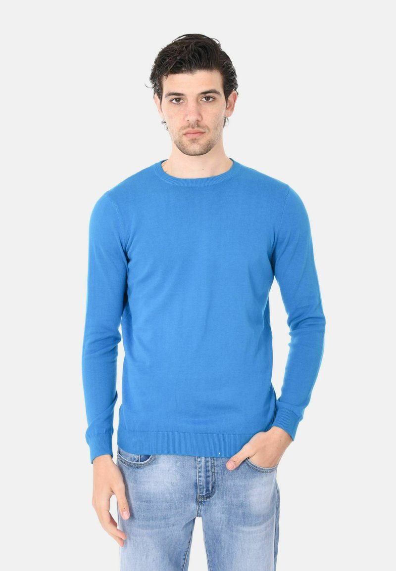 Maglione blu a maniche lunghe con colletto rotondo, realizzato in materiale liscio. Polsini e orlo a coste, design aderente, abbinato a jeans azzurri.