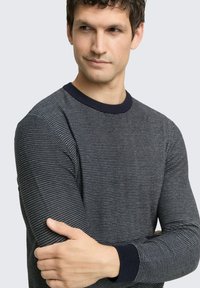 Navy-blau gestrickter Pullover mit strukturiertem Muster, kontrastierendem dunkelfarbenem Kragen und gerippten Bündchen; figurnahe Passform mit langen Ärmeln.