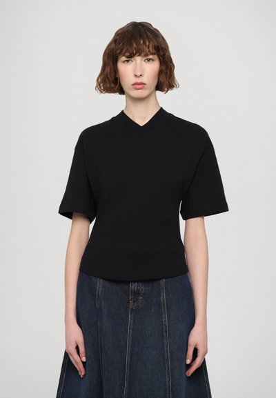 Haut noir à manches courtes et décolleté en V, en tissu lisse, cintré à la taille, avec un design minimaliste et un marquage subtil sur le côté.