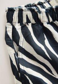 Elastic waistband with black and white zebra stripes fabric and visible stitching on a piece of clothing.