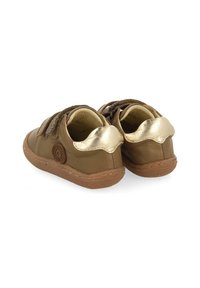 Zapatos de cuero marrón con tacón metálico dorado y costuras decorativas. Correas de velcro y detalle de logotipo redondo en el costado. Suela flexible.