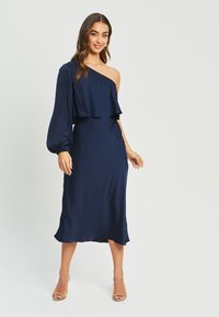 Navy satin dress with one shoulder design, ruffled bodice, and a smooth, fitted silhouette. Features a midi length and soft texture.