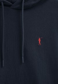 Marinblå hoodie med en röd broderad golfare-logotyp, lås för huva och texturerat tyg med ribbade ärmslut och nederkant.