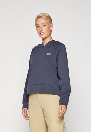 Sudadera corta de color azul marino hecha de tela suave, con capucha, mangas largas y un pequeño parche de logo en el pecho.