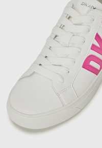 Adidași albi din piele netedă cu accente roz. Prezintă limbă căptușită, talpă din cauciuc și șireturi albe plate. Logo-ul DKNY este vizibil.