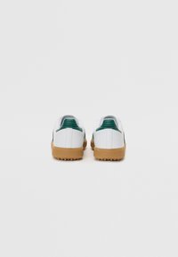 White sneakers with green accents, rubber soles, and textured detailing at the heel. Features a sleek design and round toe shape.