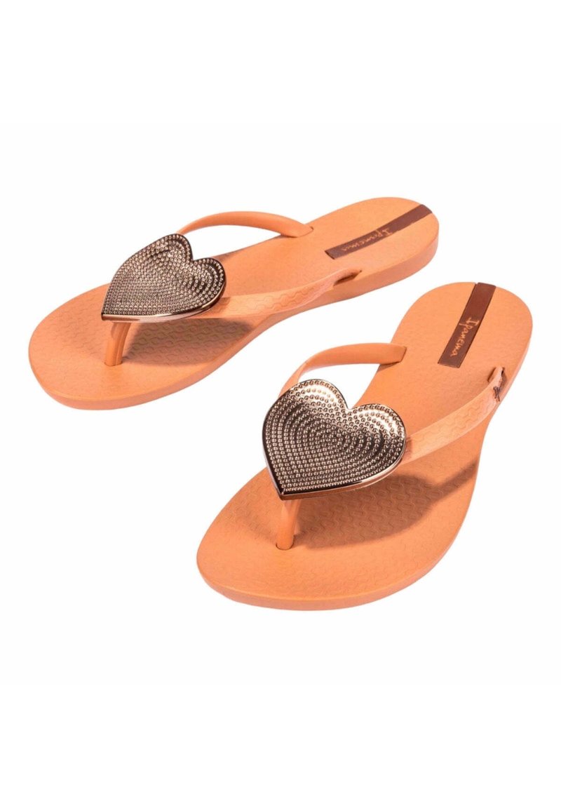 Chanclas naranjas con una suela texturizada, que presentan un adorno metálico con forma de corazón decorado con diamantes de imitación en la tira.