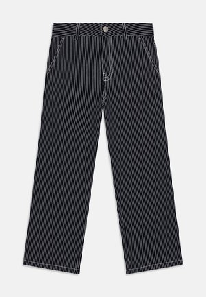 Široké kalhoty v tmavě námořnické barvě s bílými vertikálními pruhy. Disponují pěti kapsami, poutky na opasek a zavíráním na předním kovovém knoflíku.