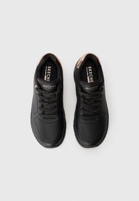 Scarpe sportive nere con una tomaia sintetica liscia, dettagli testurizzati e lacci scuri. Presentano una soletta imbottita e un marchio discreto.
