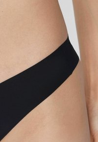 Czarne majtki bikini o gładkiej fakturze i minimalistycznym designie. Posiadają niską talię i bezszwowy pas, co zapewnia schludny wygląd.