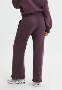 Lila bomullssweatpants med relaxed fit, med en sidoklyfta i fållen. Matchas med silverfärgad träningsskor.