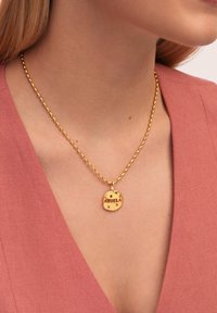 Goldene Halskette mit einem runden Anhänger, der mit "ABUELA" graviert ist und bunten Akzentsteinen verziert ist, hängend an einer gedrehten Kette.
